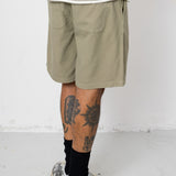 Man wearing striped t-shirt and beige shorts in front of white wall
