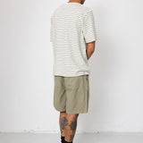 Man wearing striped t-shirt and beige shorts in front of white wall