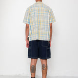 Person wearing a plaid shirt and dark shorts against a white background