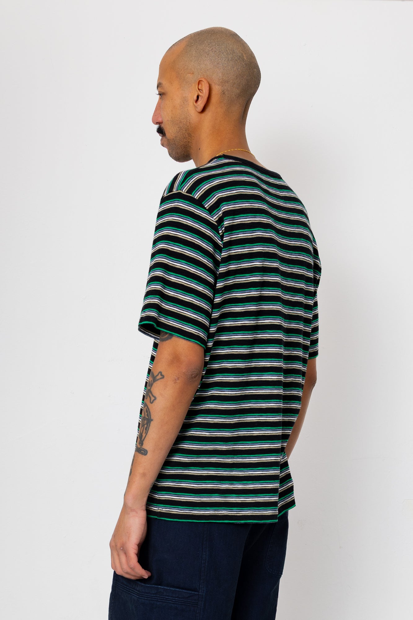 Man wearing striped t-shirt and navy shorts against light grey background