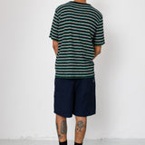 Man wearing striped t-shirt and navy shorts against light grey background