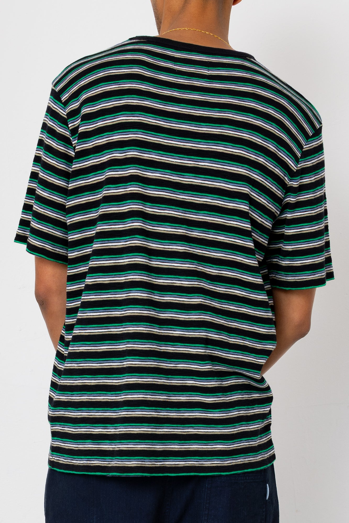 Man wearing striped t-shirt and navy shorts against light grey background