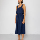 Woman wearing a navy blue sleeveless top and textured skirt against a white background