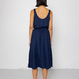 Woman wearing a navy blue sleeveless top and textured skirt against a white background