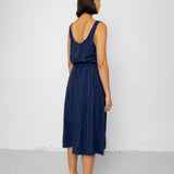 Woman wearing a navy blue sleeveless top and textured skirt against a white background