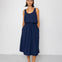 Woman wearing a navy blue sleeveless top and textured skirt against a white background