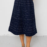 Person wearing a navy patterned skirt with a white background