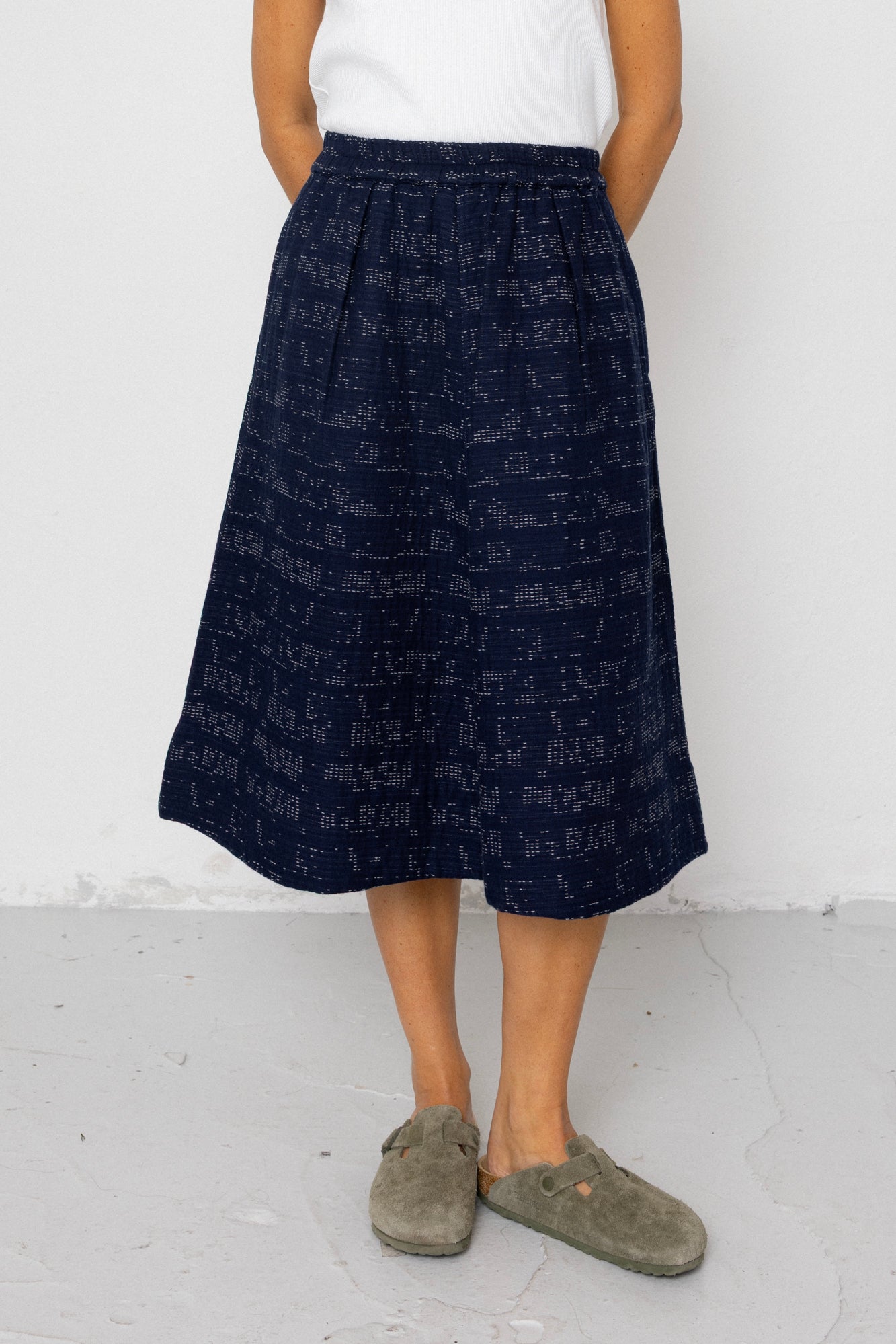 Person wearing a navy patterned skirt with a white background