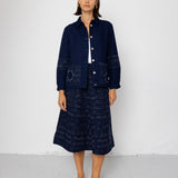 Person wearing a dark blue outfit with a jacket and skirt on a white background