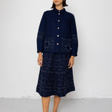 Person wearing a navy blue outfit with a long skirt against a white background