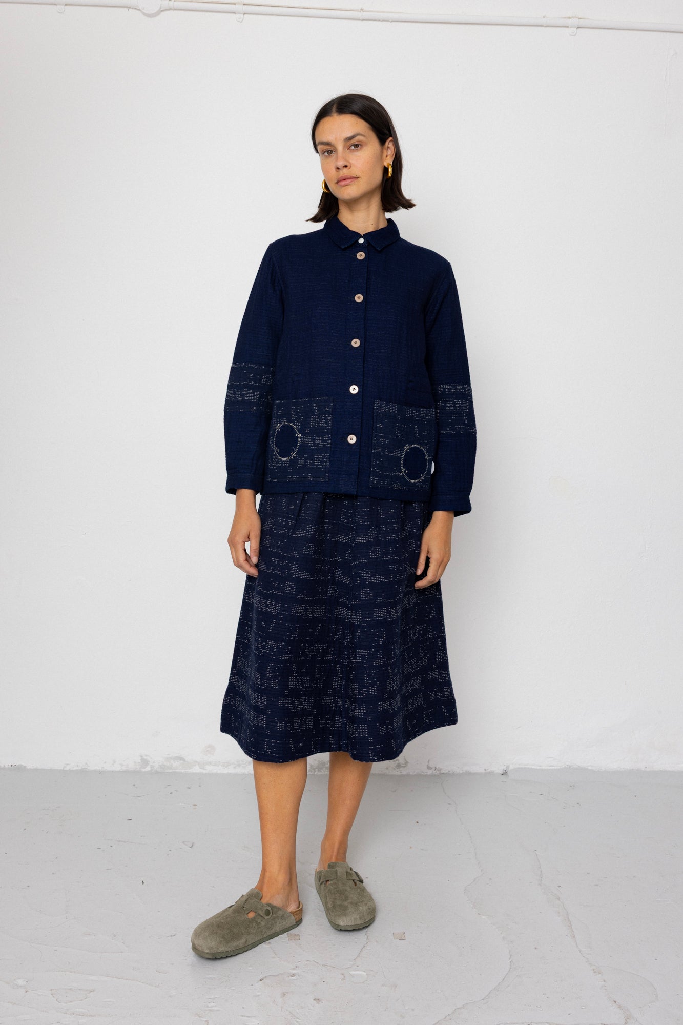 Person wearing a navy blue outfit with a long skirt against a white background