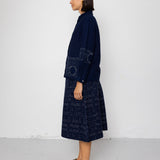 Woman wearing a dark blue outfit with a pattern against a white background