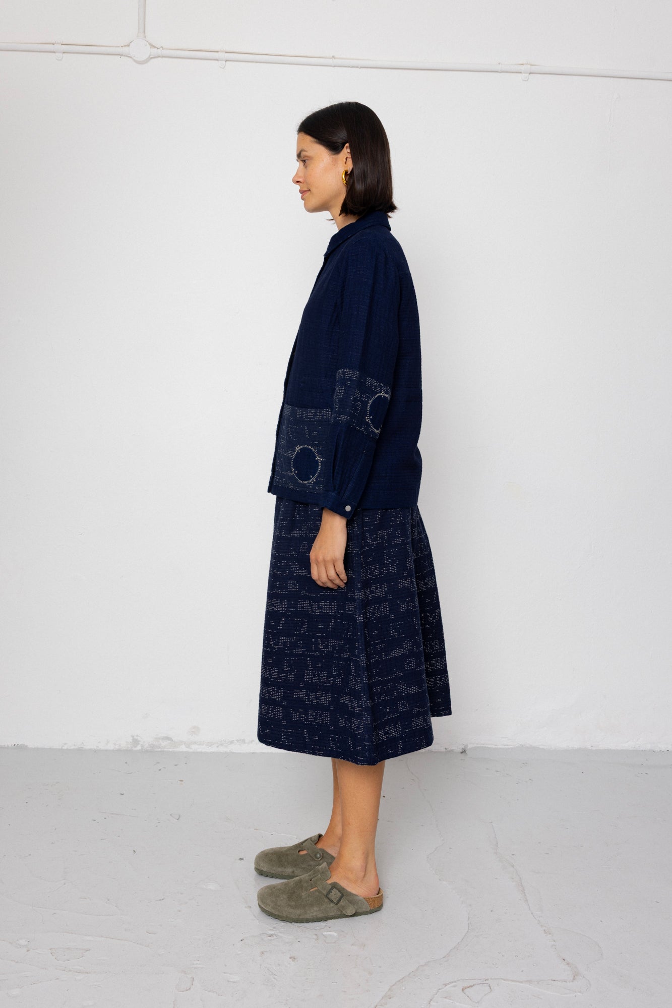 Woman wearing a dark blue outfit with a pattern against a white background