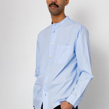 Man wearing a light blue shirt and black pants against a white background