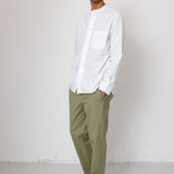 Man wearing a white shirt and green pants against a white background