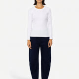 Woman wearing long sleeve white t-shirt and navy trousers