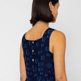 Woman wearing a navy blue dress with a geometric pattern on a white background