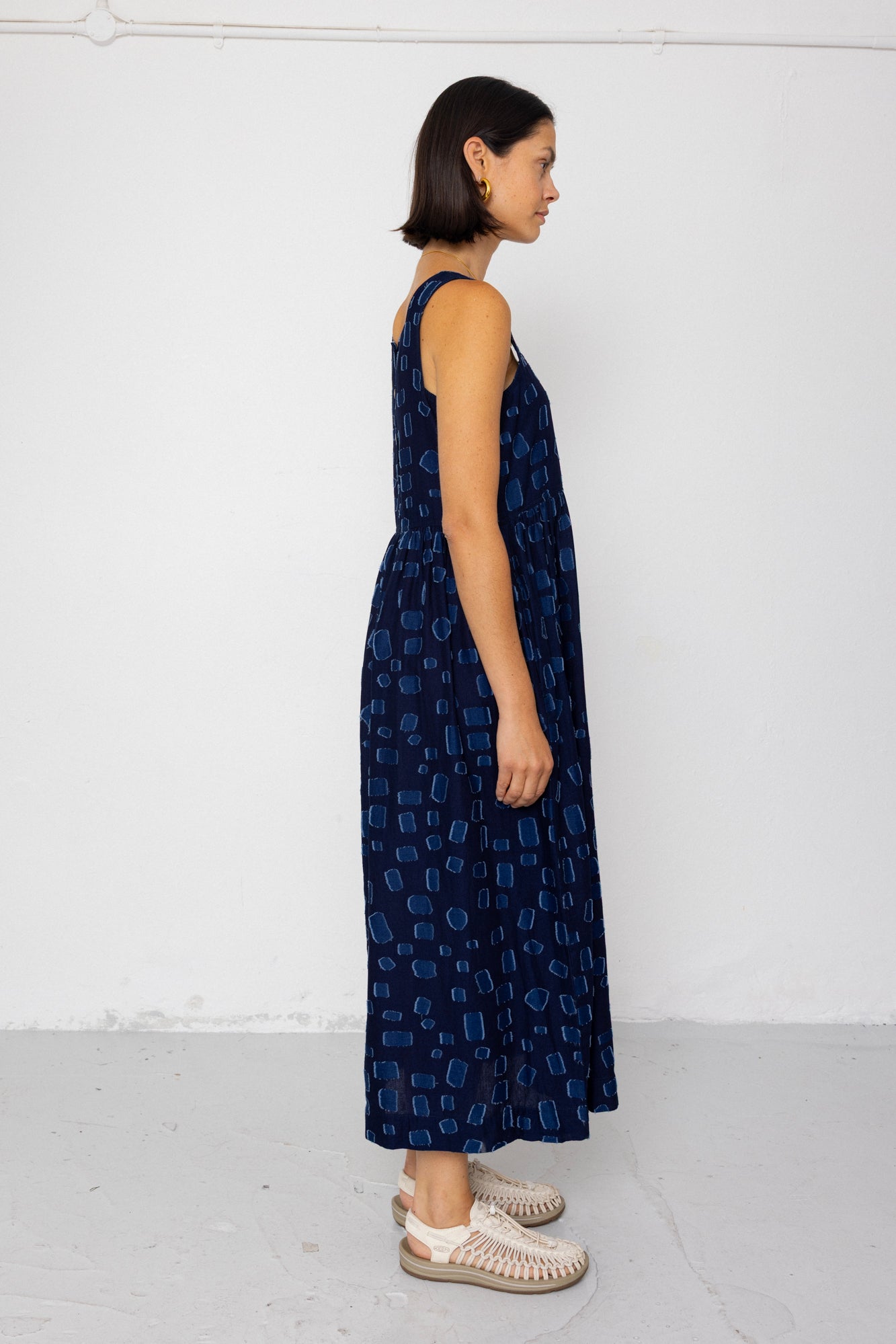 Woman wearing a dark blue patterned dress against a white background