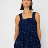 Woman wearing a navy blue sleeveless dress with geometric pattern on a white background