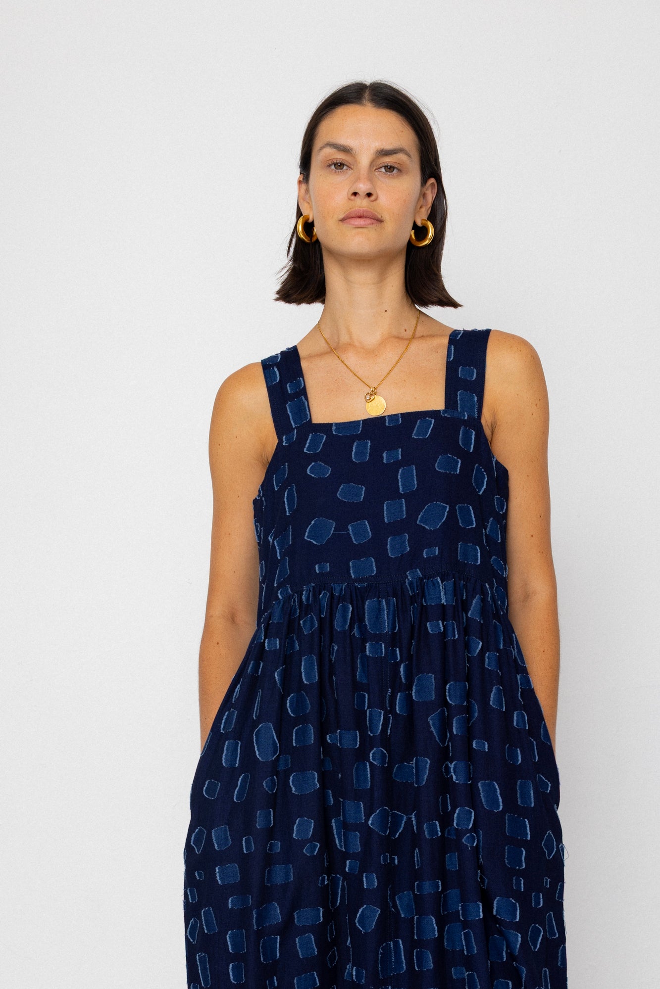 Woman wearing a navy blue sleeveless dress with geometric pattern on a white background