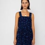 Woman wearing a navy blue patterned dress against a white background