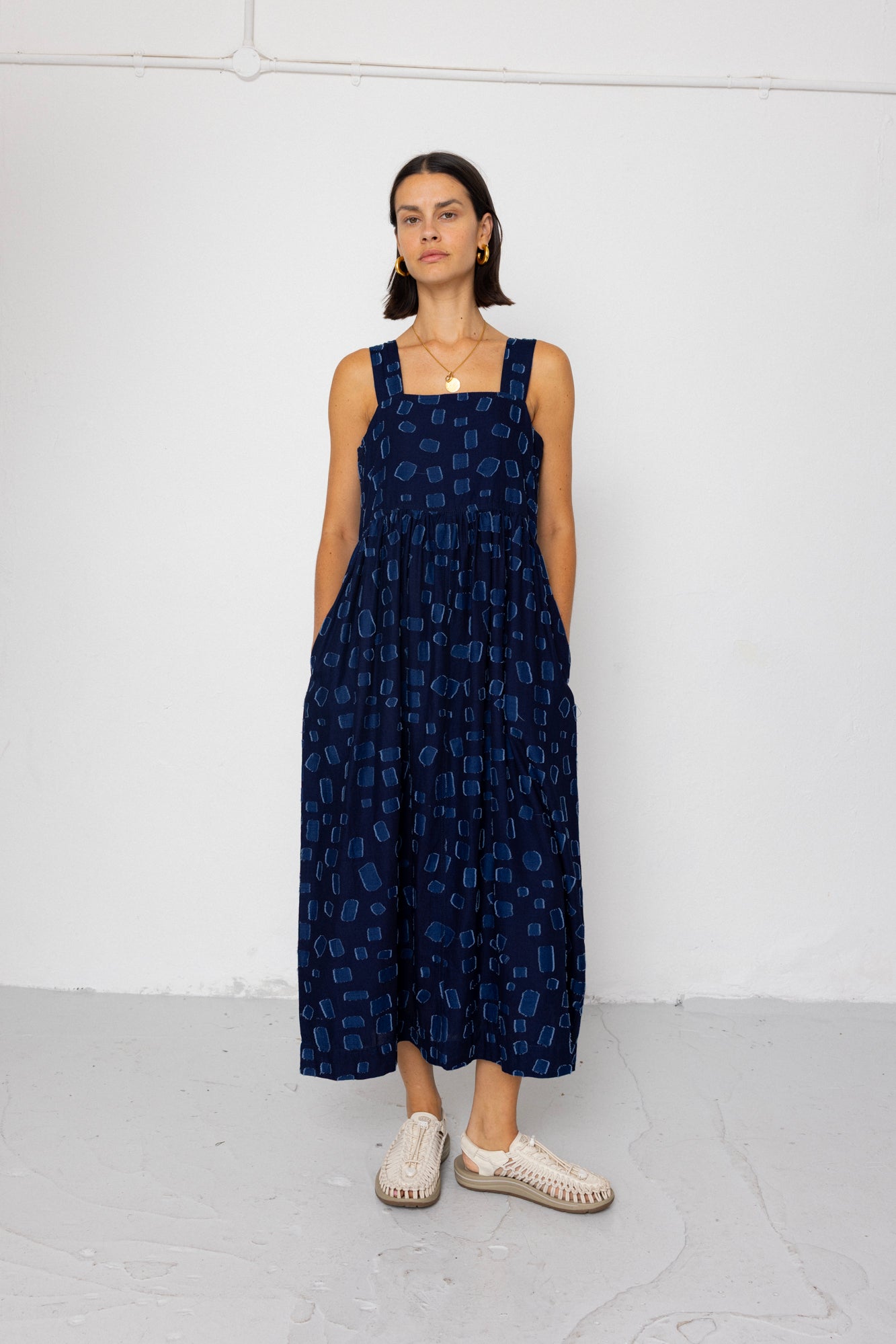 Woman wearing a navy blue patterned dress against a white background