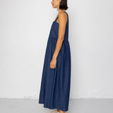 Woman wearing a blue dress standing against a white wall.