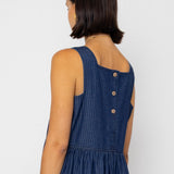 Woman wearing a blue striped denim dress with button details on a white background