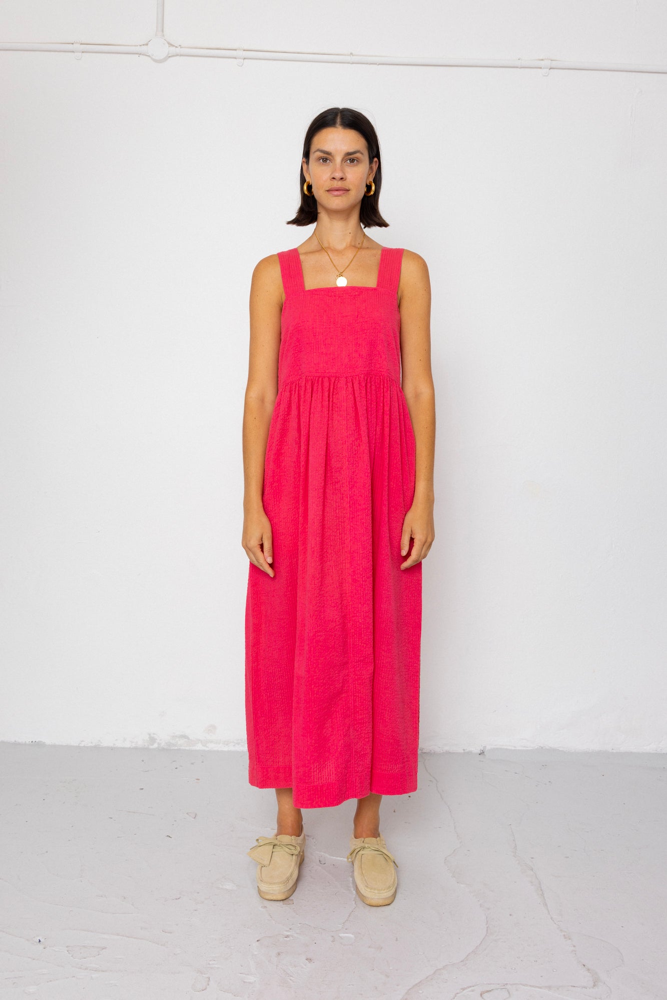 Woman wearing a pink dress standing against a white background