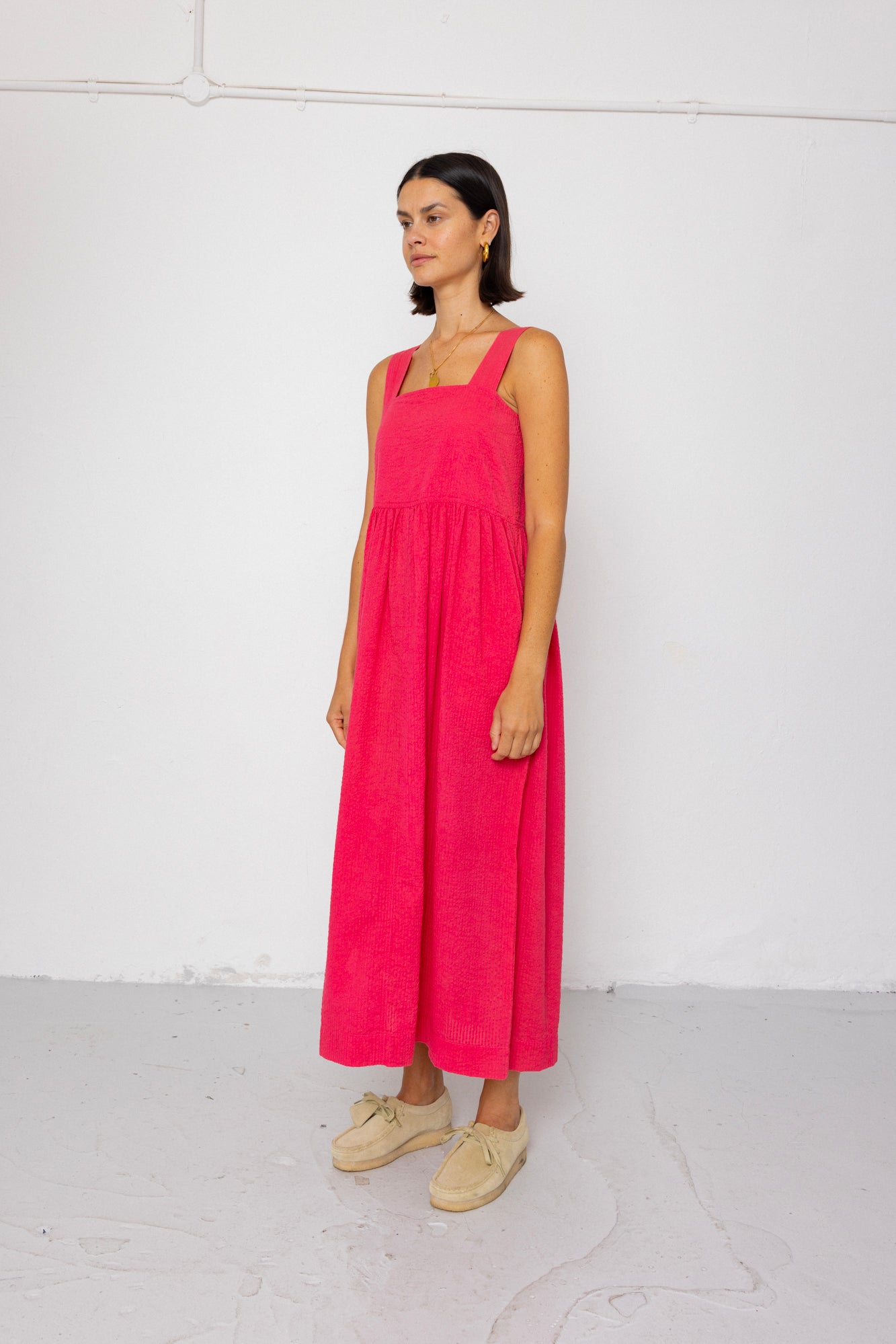 Woman wearing a pink dress standing against a white background