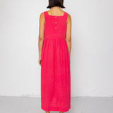 Person wearing a pink dress with buttons on a white background