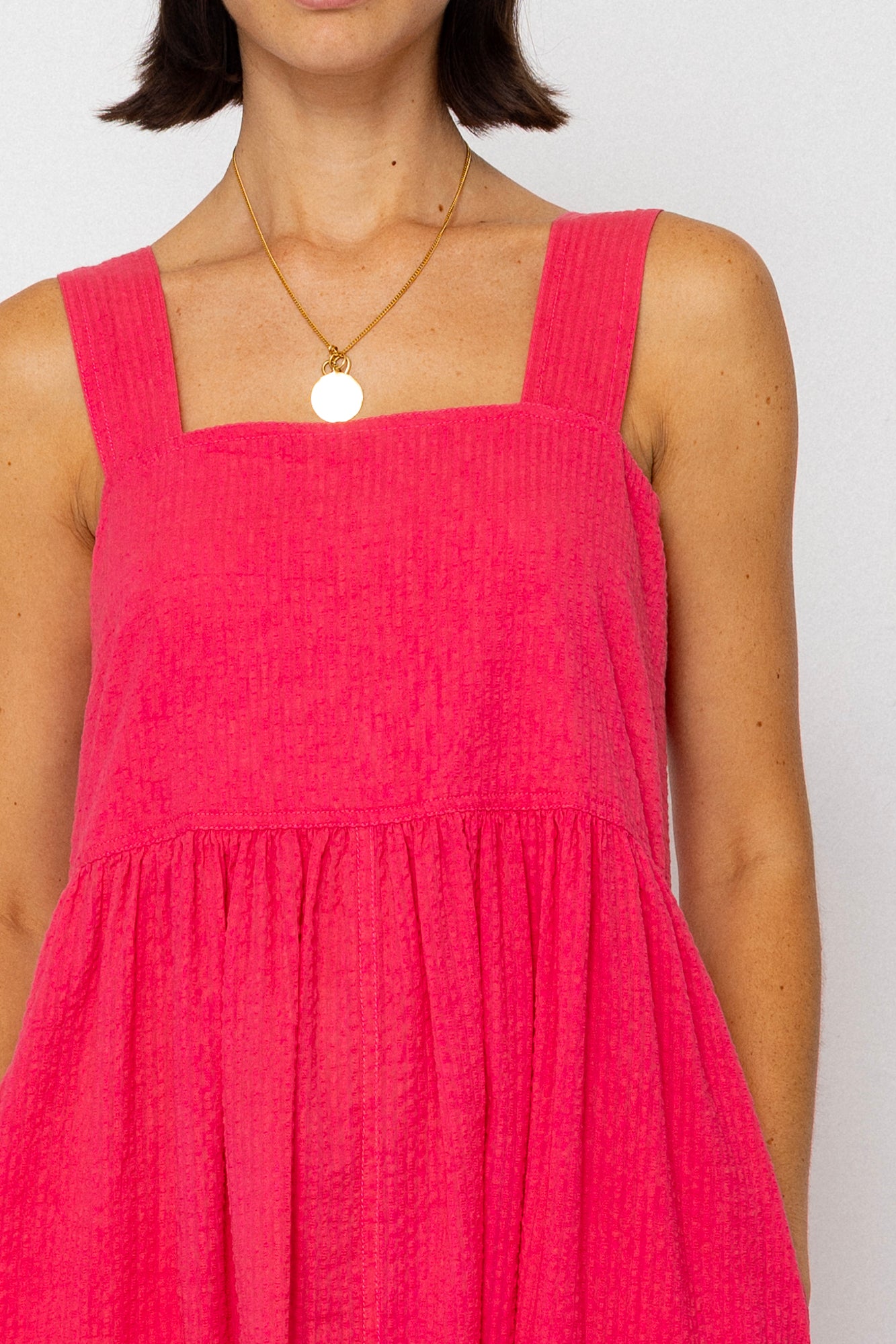 Person wearing a pink dress with a white background