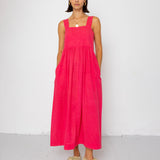 Woman wearing a pink dress standing against a white background