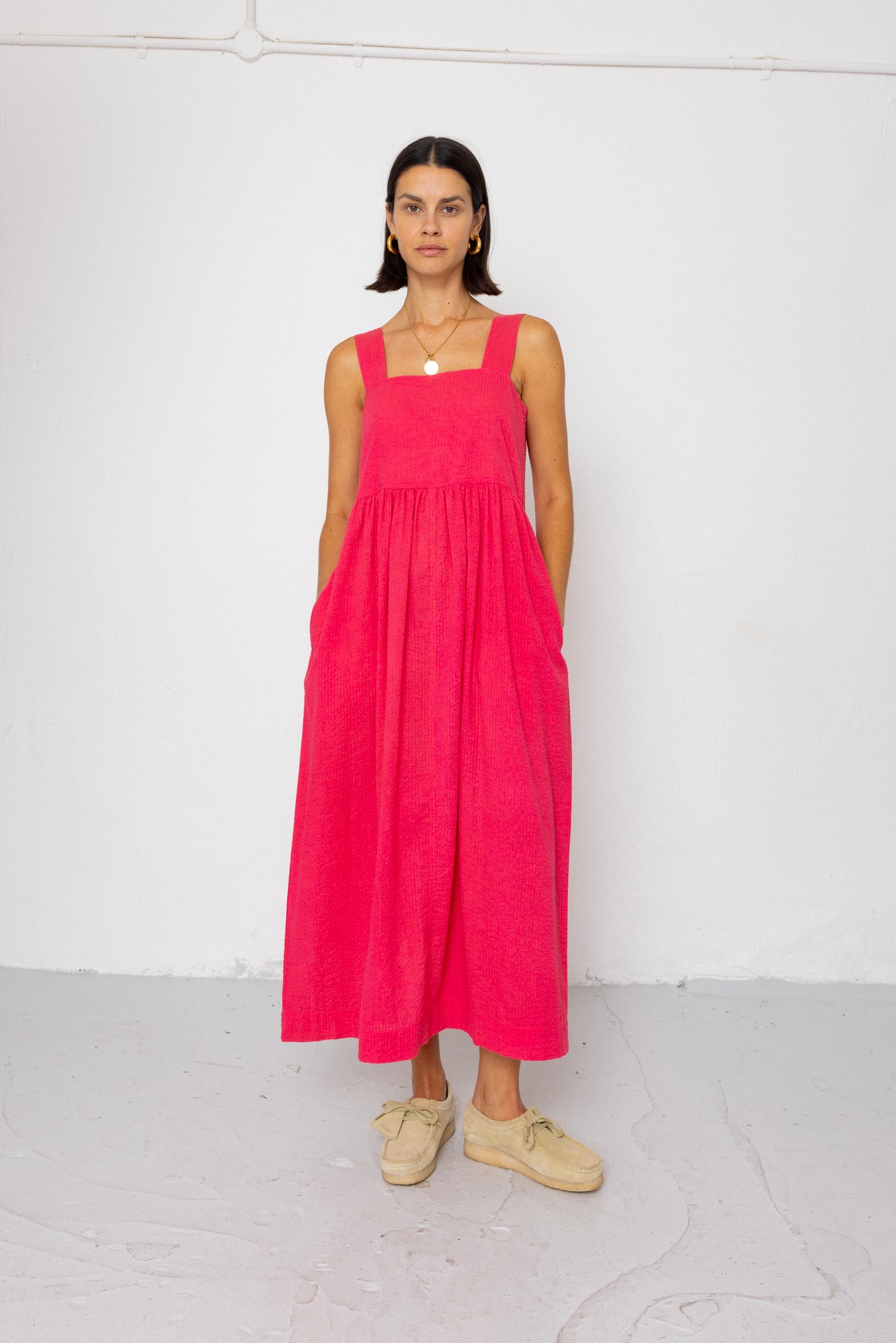 Woman wearing a pink dress standing against a white background