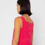 Woman wearing a pink dress with buttons on a white background