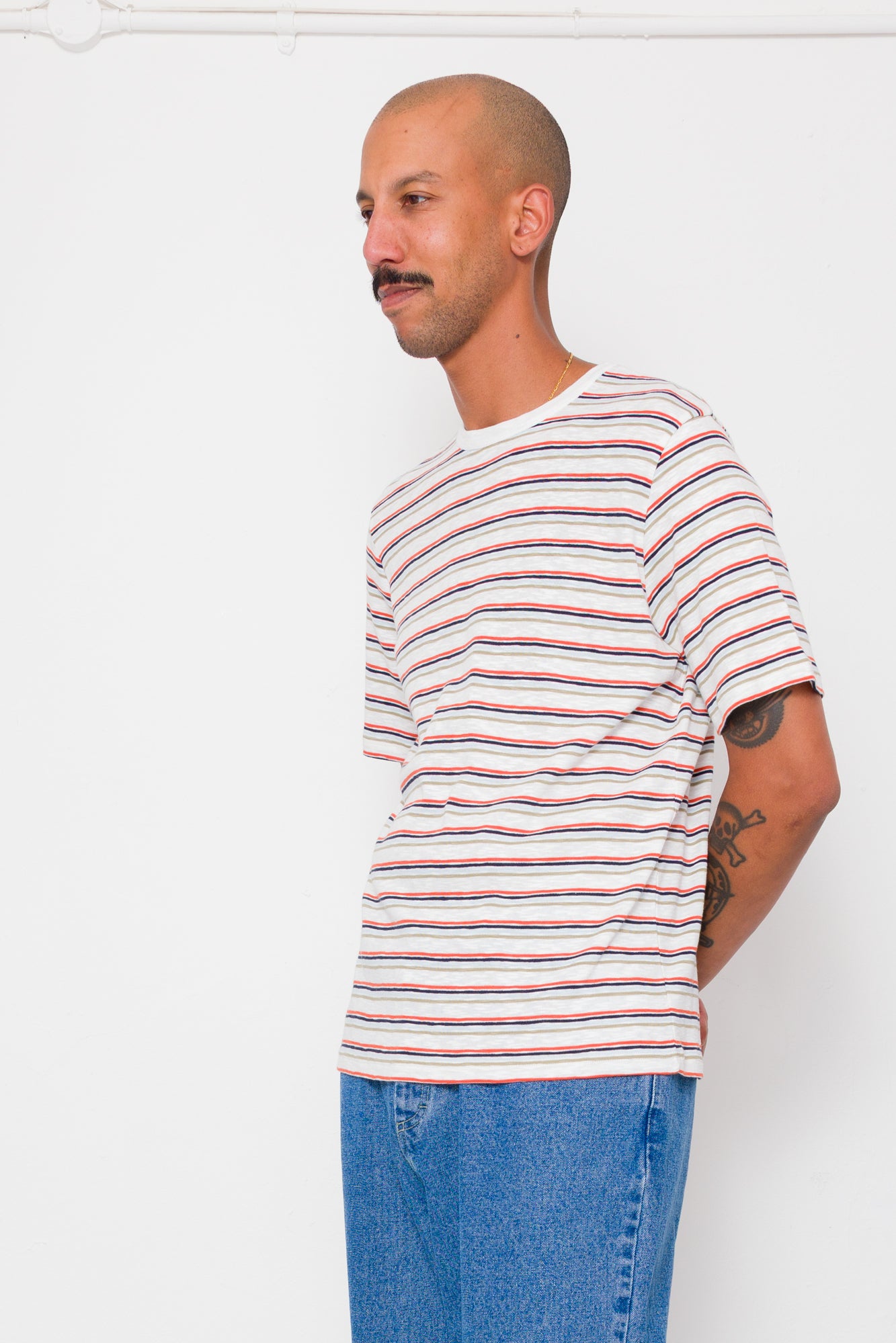 Man wearing a striped shirt and jeans against a white background