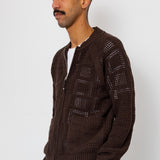 Man wearing a brown knitted cardigan against a white background