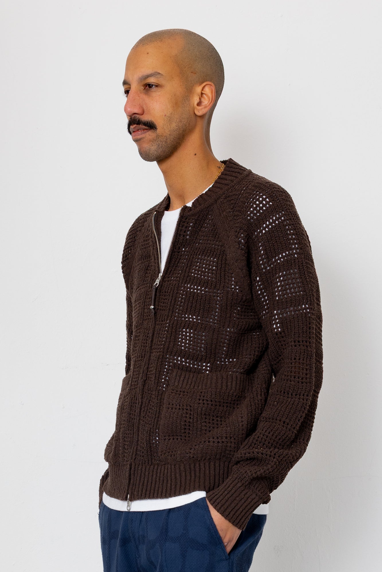 Man wearing a brown knitted cardigan against a white background