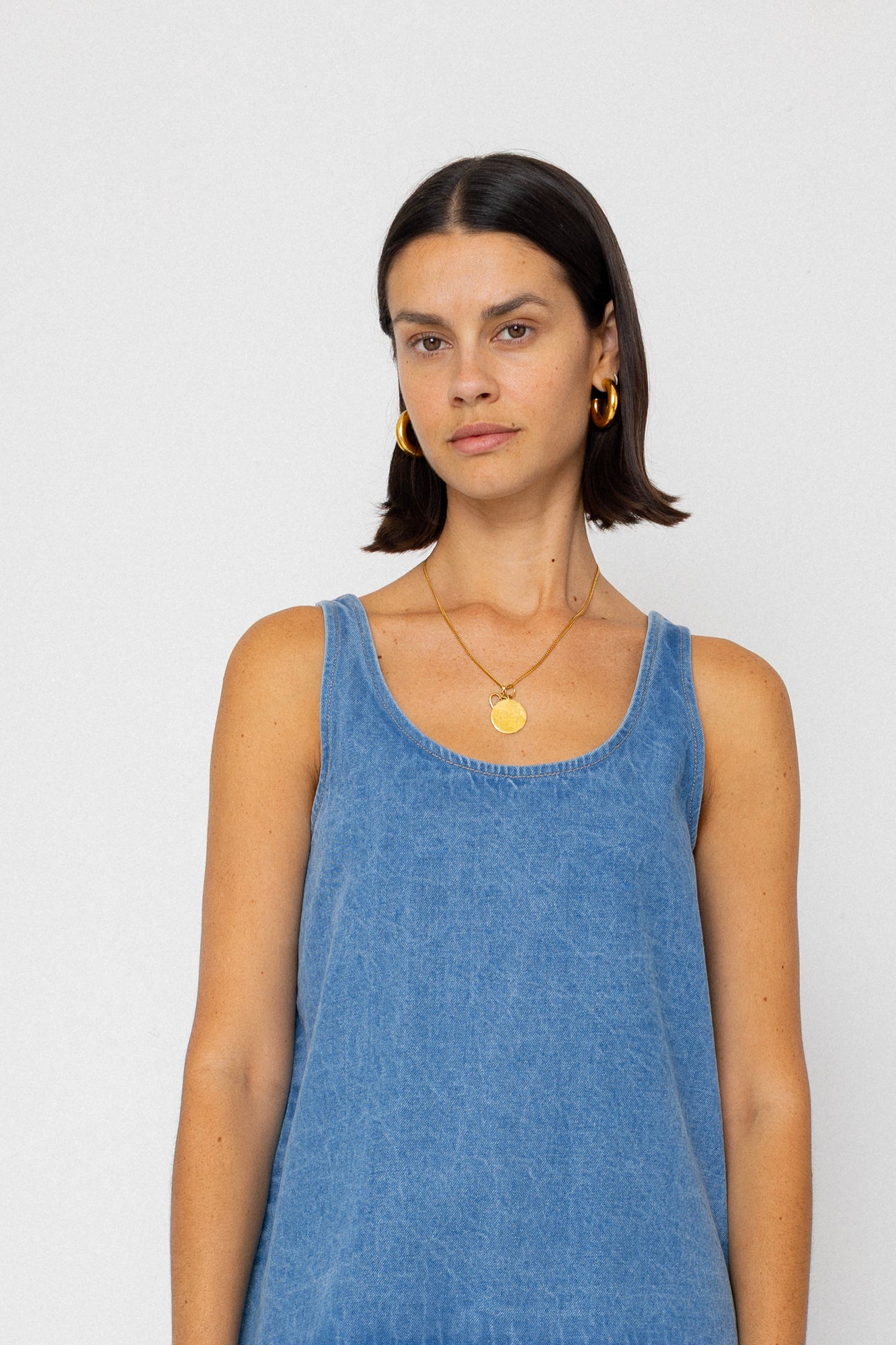 Woman wearing a denim tank top on a plain background