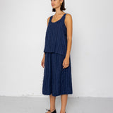 Woman wearing a navy blue sleeveless top and skirt set against a white background