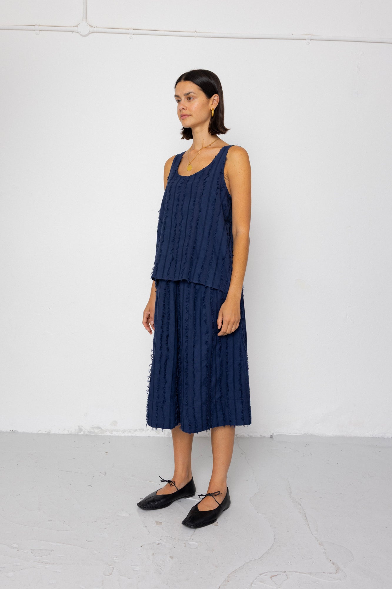 Woman wearing a navy blue sleeveless top and skirt set against a white background