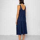 Woman wearing a navy blue sleeveless top and skirt against a white background
