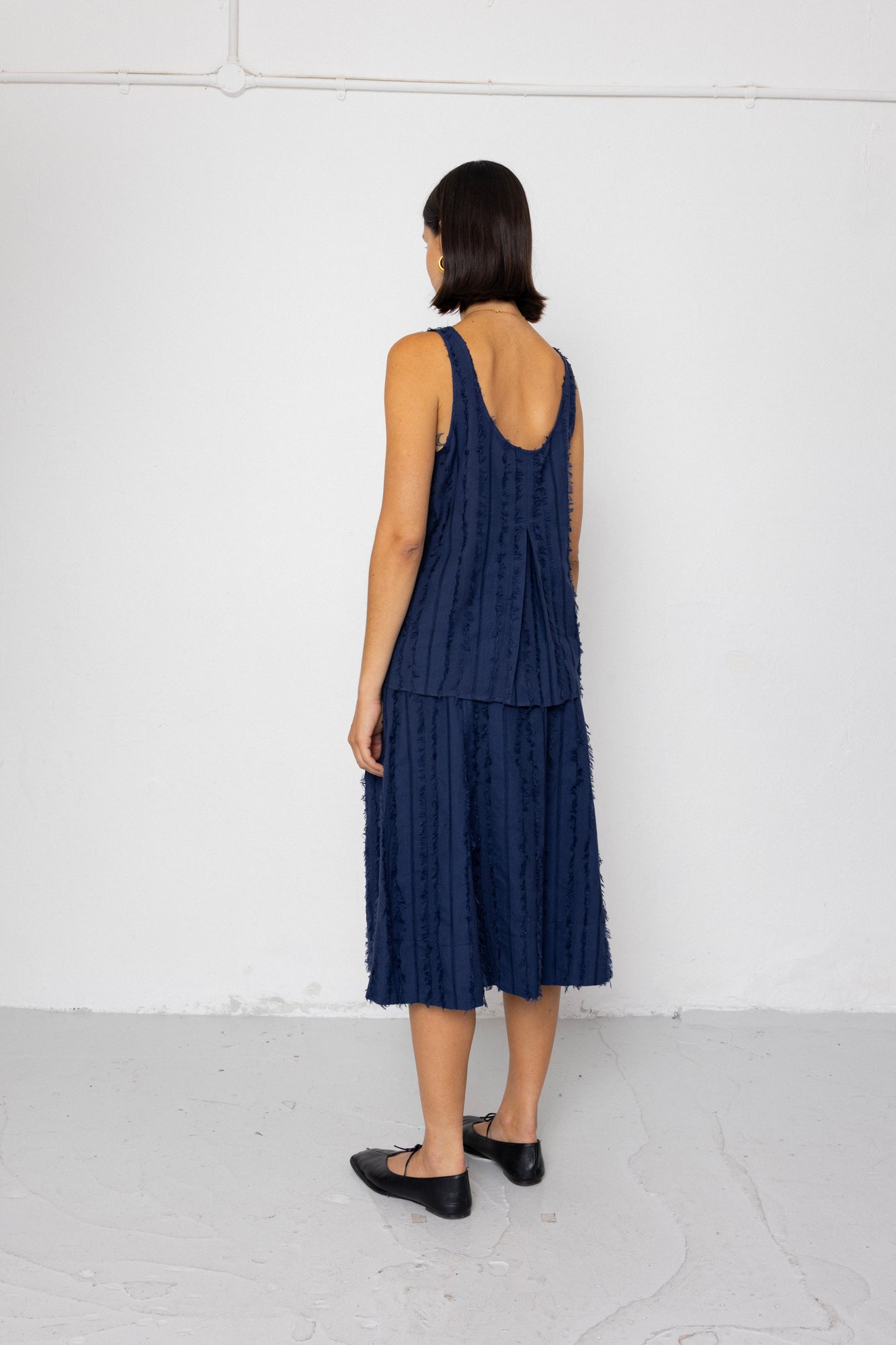 Woman wearing a navy blue sleeveless top and skirt against a white background