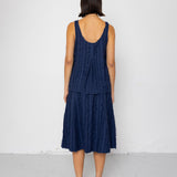 Woman wearing a navy blue sleeveless top and skirt against a white background