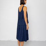 Woman wearing a navy blue sleeveless top and skirt against a white background