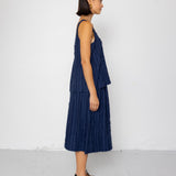 Woman wearing a navy blue sleeveless top and skirt against a white background