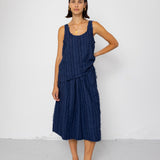 Woman wearing a navy blue sleeveless top and skirt against a white background