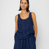 Woman wearing a navy blue sleeveless top and skirt against a white background