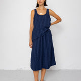 Woman wearing a navy blue sleeveless top and skirt against a white background