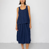 Woman wearing a navy blue sleeveless top and skirt against a white background
